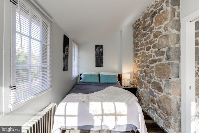 bedroom featuring radiator heating unit, lofted ceiling, and hardwood / wood-style floors