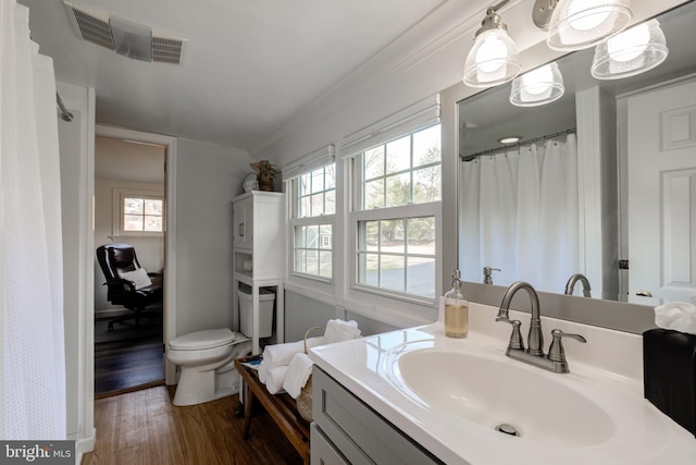 bathroom with ornamental molding, vanity, wood-type flooring, and toilet