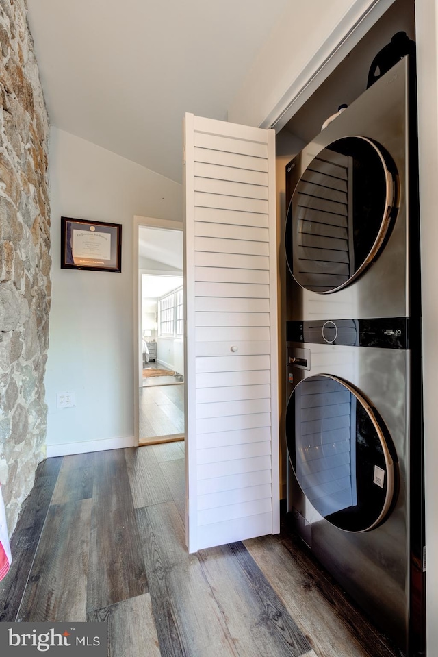 laundry room featuring dark hardwood / wood-style flooring and stacked washer and clothes dryer