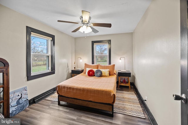 bedroom with hardwood / wood-style flooring, multiple windows, and ceiling fan