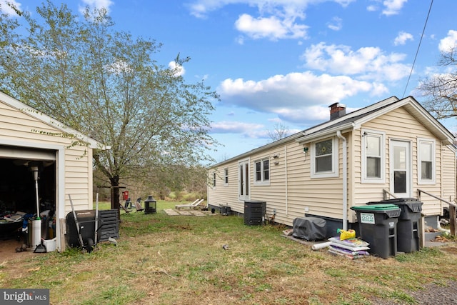 view of home's exterior with central air condition unit, a yard, and a garage