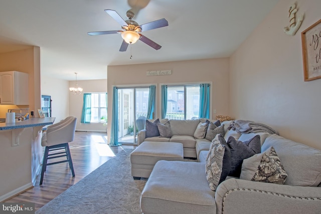 living room with light wood-type flooring, ceiling fan with notable chandelier, and a healthy amount of sunlight