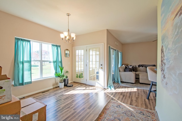 doorway to outside with an inviting chandelier and light hardwood / wood-style floors