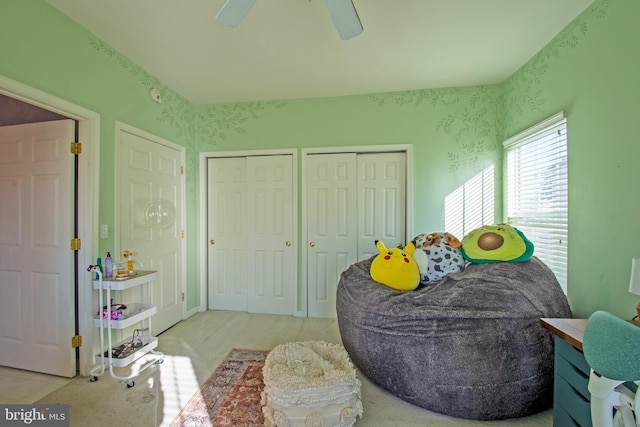 bedroom with multiple closets, light carpet, and ceiling fan