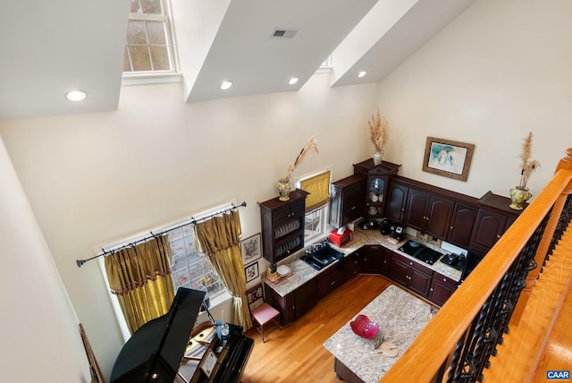 living room featuring a towering ceiling, light wood-type flooring, and a healthy amount of sunlight