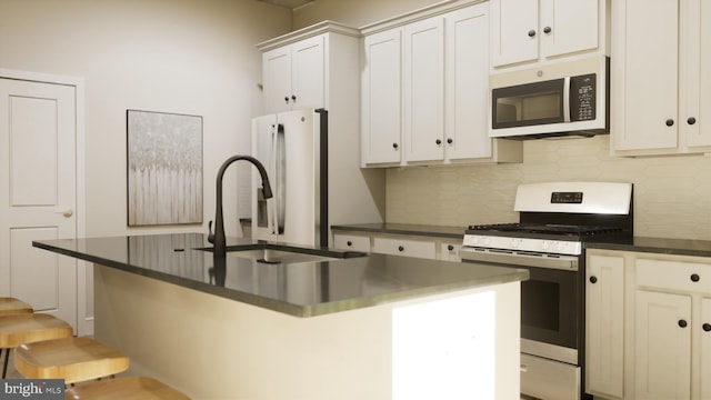 kitchen featuring a center island with sink, sink, appliances with stainless steel finishes, backsplash, and white cabinets