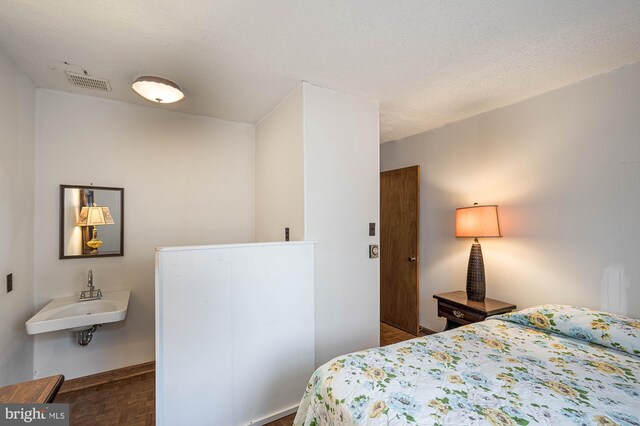 bedroom featuring dark parquet flooring, a textured ceiling, and sink