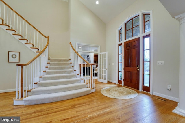 entryway featuring hardwood / wood-style floors, high vaulted ceiling, and decorative columns