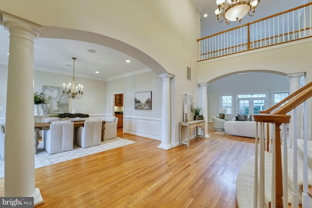 17061 Spring Creek Ln, Leesburg, VA 20176 - foyer entrance featuring a chandelier, light wood finished floors, arched walkways, ornate columns, and crown molding