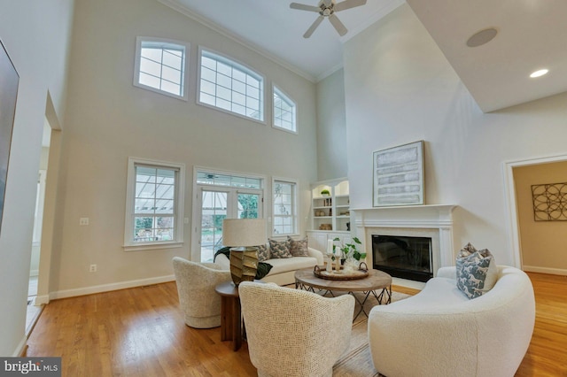 living room featuring a wealth of natural light, light hardwood / wood-style flooring, ceiling fan, and ornamental molding