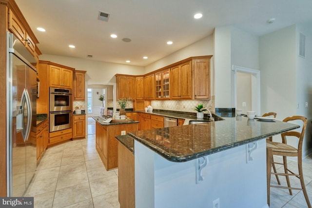 kitchen featuring a breakfast bar, stainless steel appliances, kitchen peninsula, and light tile patterned flooring