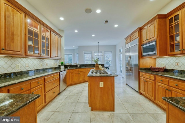 kitchen featuring built in appliances, a center island, dark stone countertops, and light tile patterned flooring