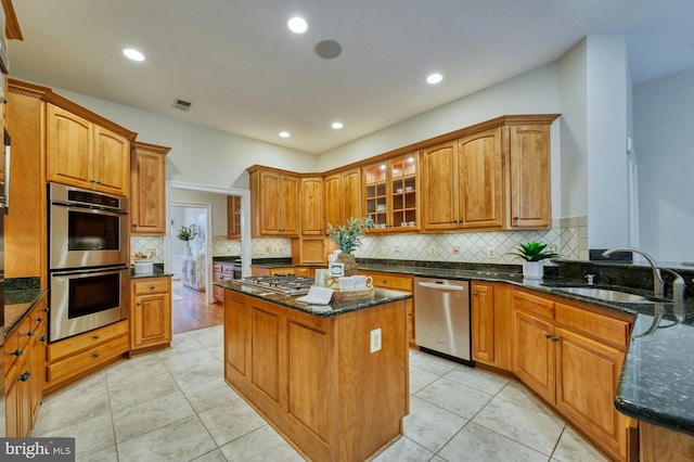 kitchen featuring a center island, dark stone counters, sink, light tile patterned floors, and stainless steel appliances