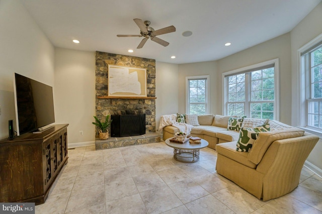 living room with a stone fireplace, ceiling fan, and light tile patterned floors