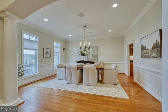 unfurnished dining area with a notable chandelier, light wood-type flooring, ornamental molding, and ornate columns