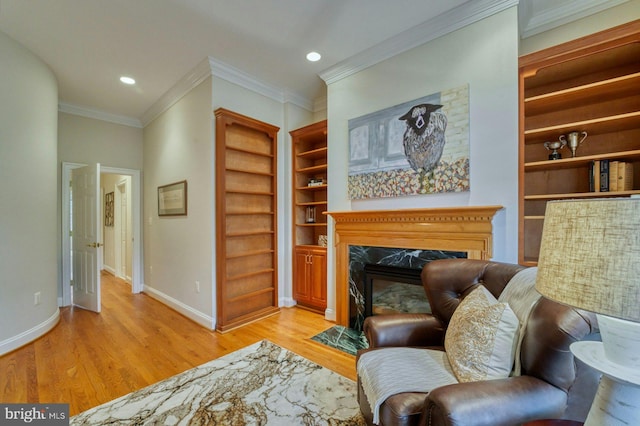 living area featuring a premium fireplace, light hardwood / wood-style floors, and ornamental molding