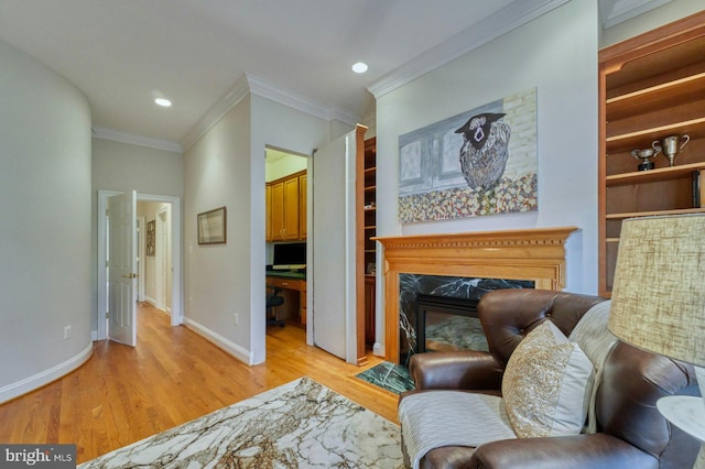 living area with a fireplace, light hardwood / wood-style floors, and ornamental molding