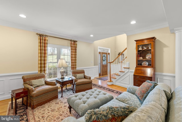 living room featuring ornate columns, crown molding, and light hardwood / wood-style flooring