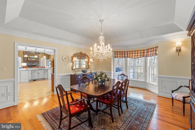 dining area featuring a tray ceiling, light hardwood / wood-style flooring, a notable chandelier, and ornamental molding