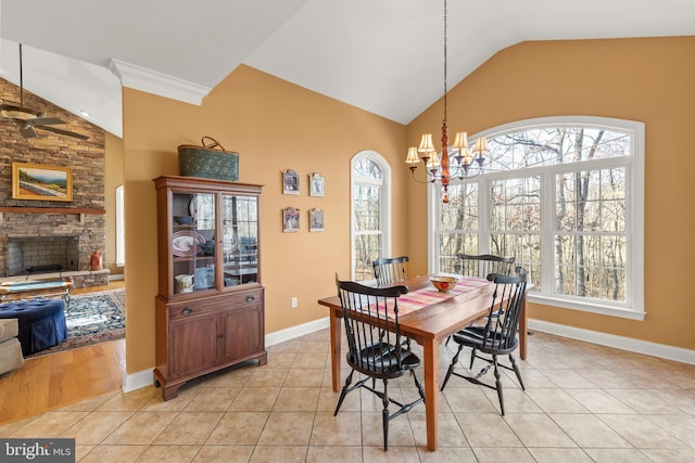 tiled dining area featuring ceiling fan with notable chandelier, lofted ceiling, a fireplace, and a wealth of natural light