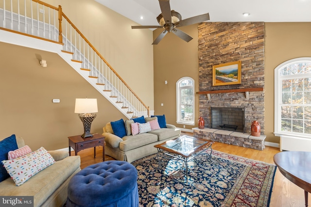 living room featuring ceiling fan, wood-type flooring, a fireplace, and high vaulted ceiling