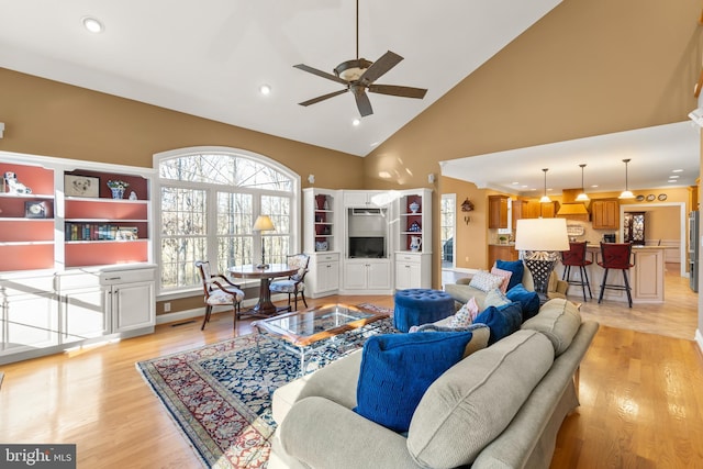 living room featuring ceiling fan, light hardwood / wood-style flooring, and high vaulted ceiling