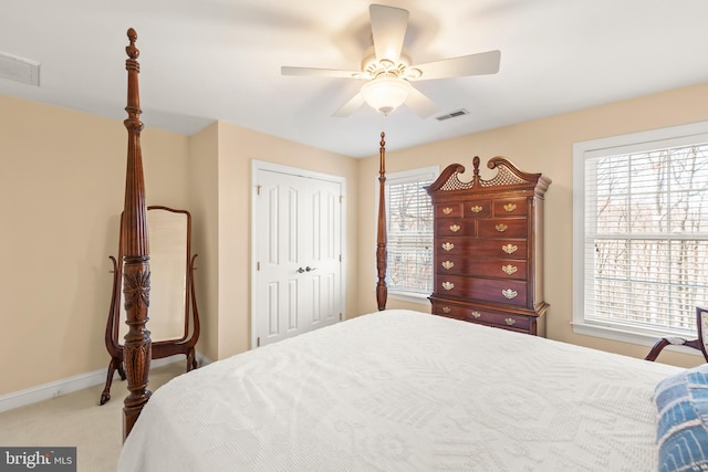 carpeted bedroom with multiple windows, ceiling fan, and a closet