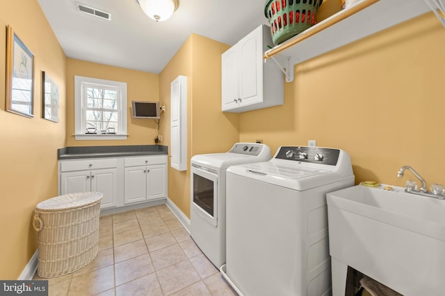 clothes washing area with cabinets, independent washer and dryer, light tile patterned floors, and sink