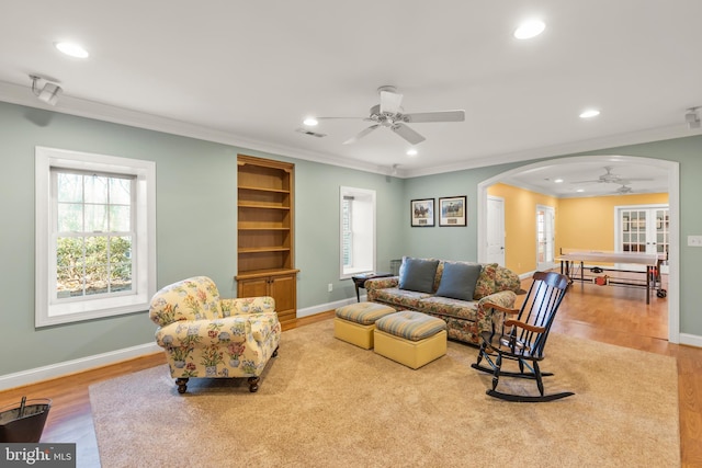 living room with french doors, light hardwood / wood-style floors, ceiling fan, and crown molding