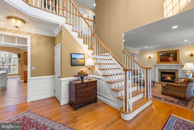 stairway with wood-type flooring, crown molding, and a high ceiling