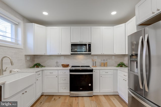 kitchen with white cabinets, sink, light hardwood / wood-style floors, and stainless steel appliances