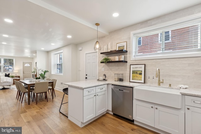 kitchen with white cabinetry, decorative light fixtures, sink, light hardwood / wood-style floors, and dishwasher