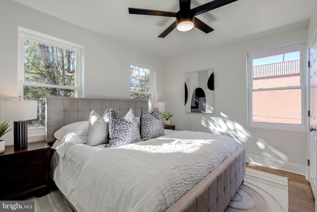 bedroom with wood-type flooring, multiple windows, and ceiling fan