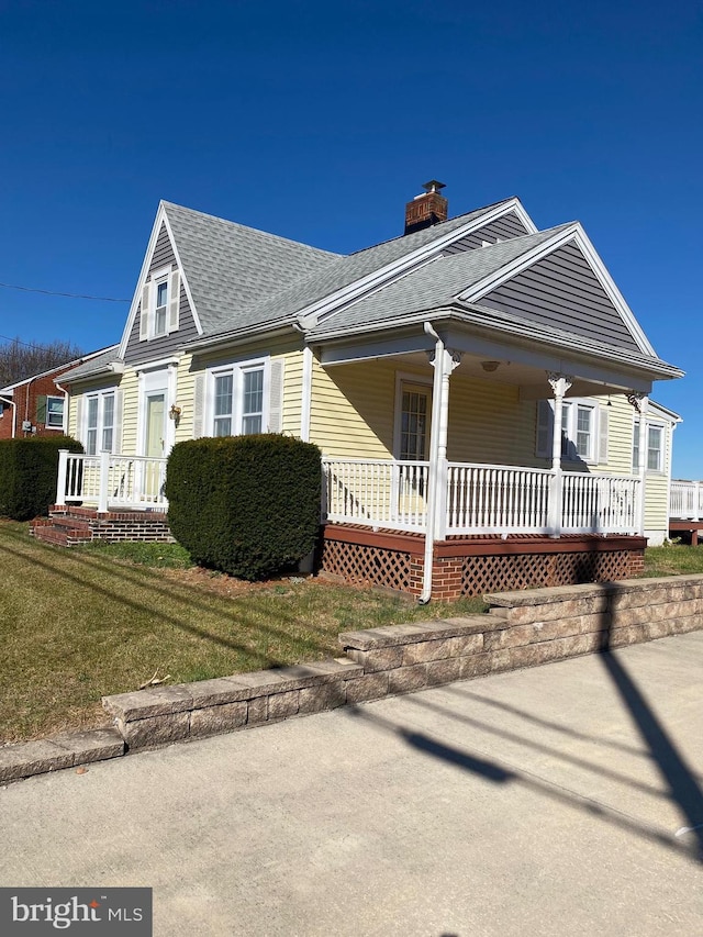 view of side of home with a lawn and covered porch