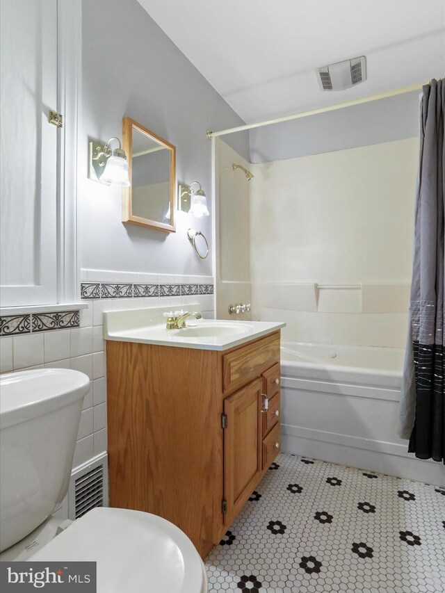 full bathroom with shower / tub combo, vanity, tile walls, tile patterned flooring, and toilet