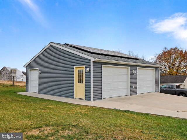 garage featuring solar panels and a lawn