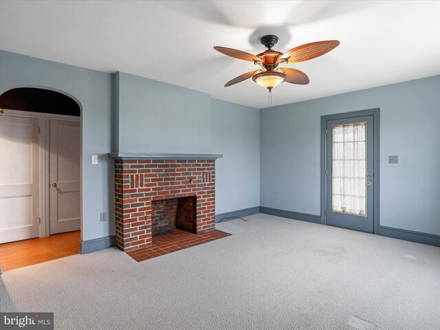 unfurnished living room featuring a fireplace, light colored carpet, and ceiling fan