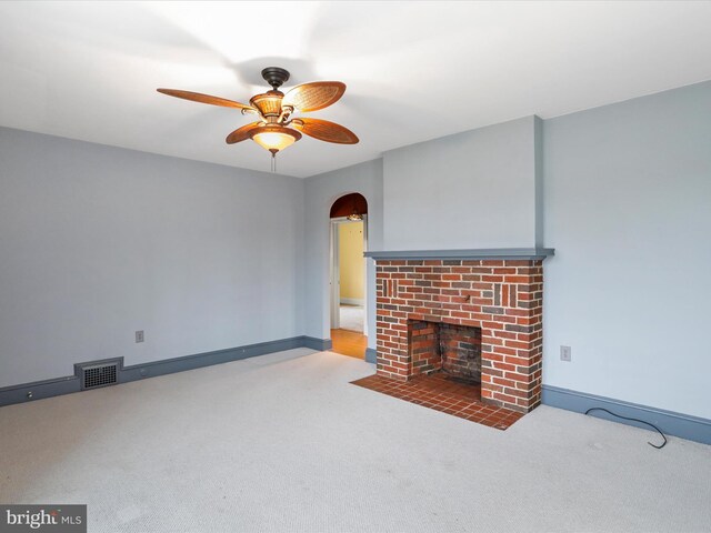 unfurnished living room with carpet flooring, ceiling fan, and a brick fireplace