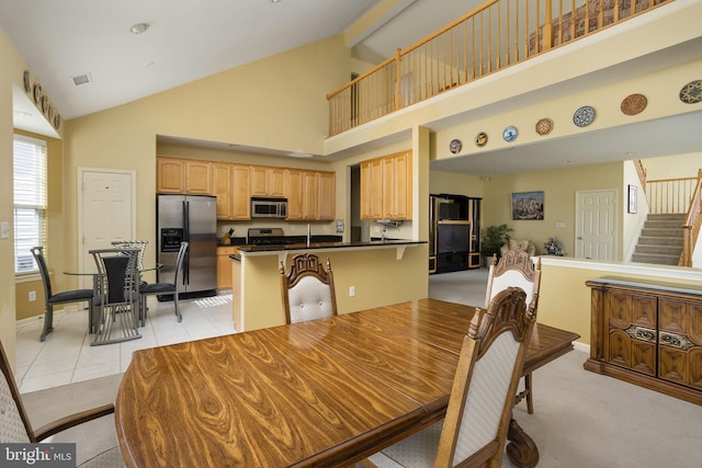 dining area with light colored carpet and high vaulted ceiling