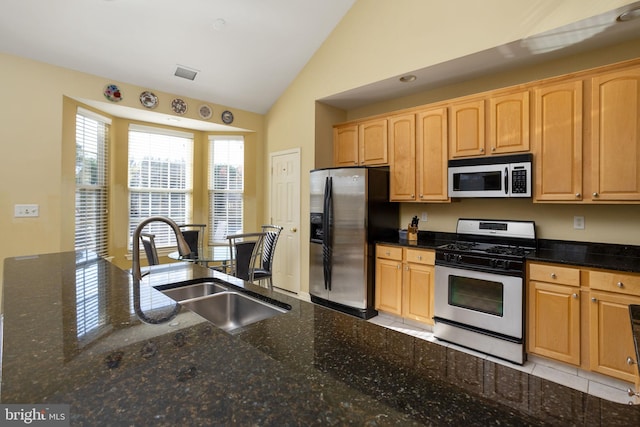 kitchen featuring dark stone countertops, sink, vaulted ceiling, and appliances with stainless steel finishes