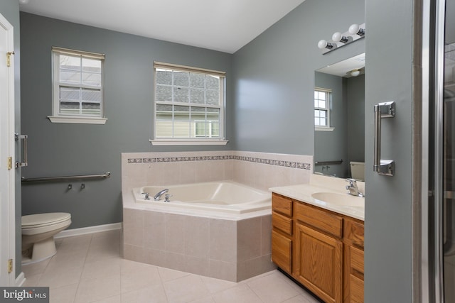 bathroom with tiled tub, vanity, tile patterned floors, and toilet