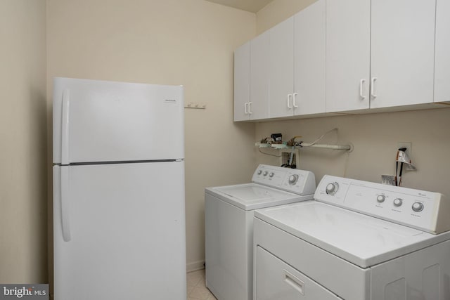 clothes washing area with cabinets and washer and clothes dryer