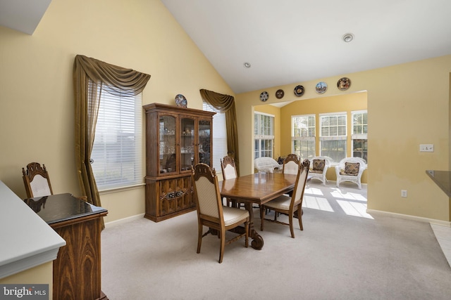 carpeted dining area featuring vaulted ceiling