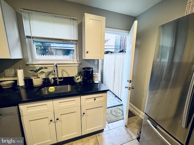 kitchen with light tile patterned flooring, stainless steel appliances, white cabinetry, and sink