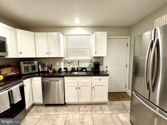 kitchen with light tile patterned floors, stainless steel appliances, white cabinetry, and sink