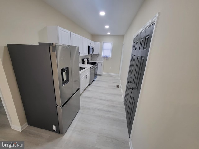 kitchen with light hardwood / wood-style flooring, decorative backsplash, white cabinets, and stainless steel appliances