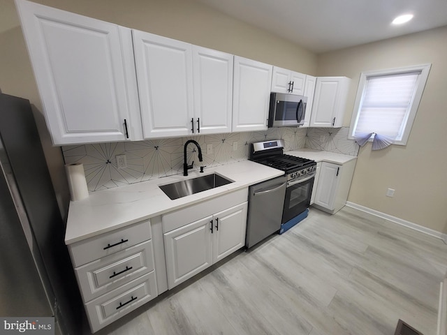 kitchen with white cabinets, appliances with stainless steel finishes, backsplash, and sink