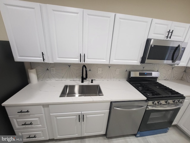 kitchen featuring white cabinets, appliances with stainless steel finishes, decorative backsplash, and sink