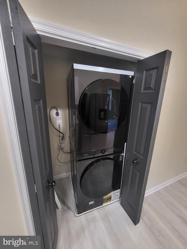 laundry room with stacked washer / dryer and light hardwood / wood-style floors