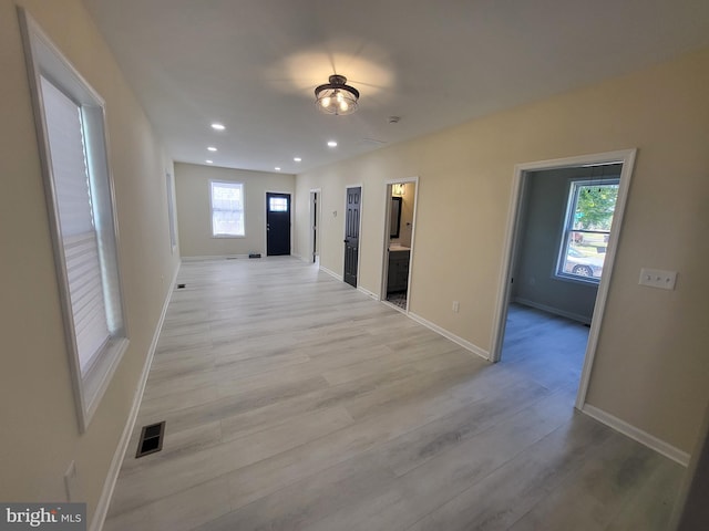 corridor with plenty of natural light and light hardwood / wood-style flooring